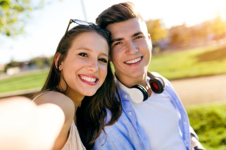 Beautiful young couple taking a selfie in the park.
